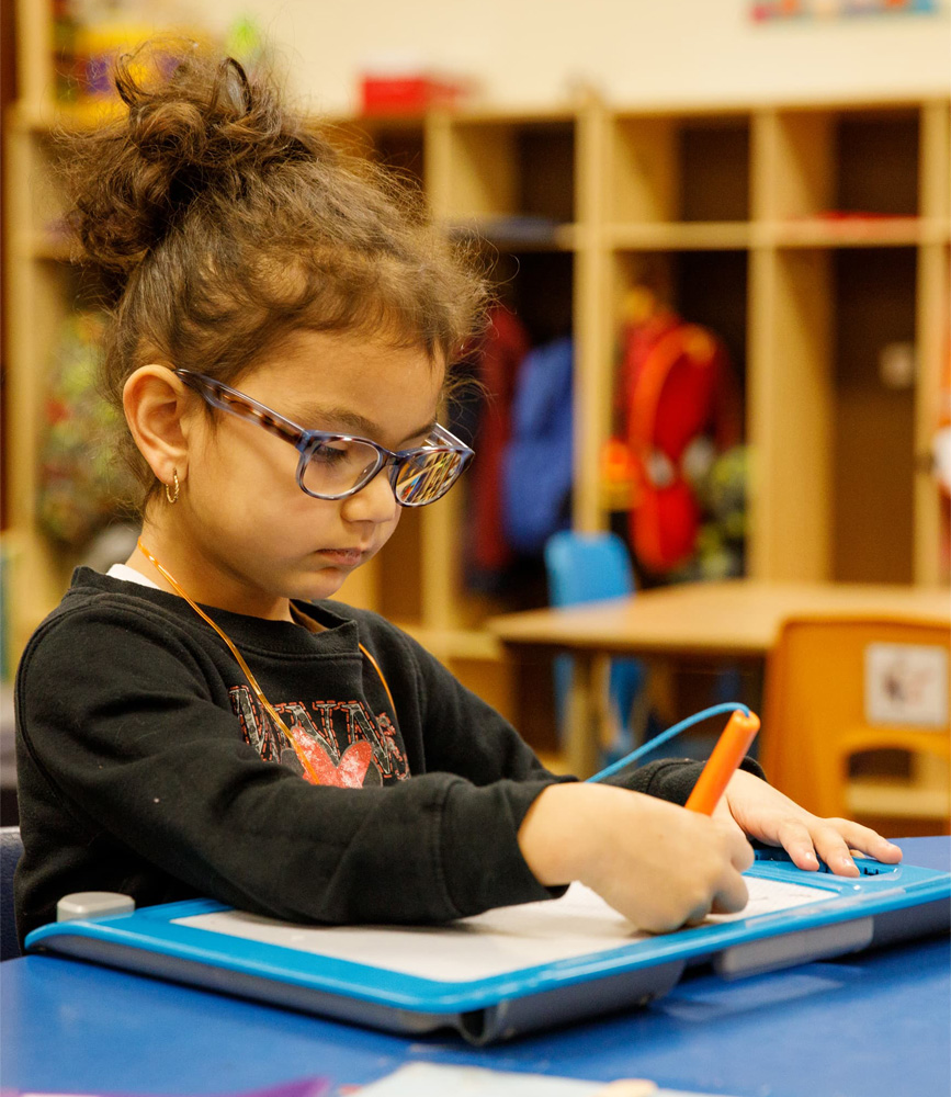 A small child writes on a smart board