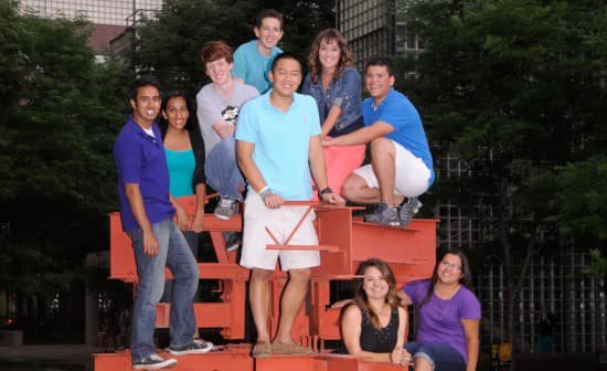 Scott Cao and other students from the class of 2017 all seated on a campus sculpture smiling.