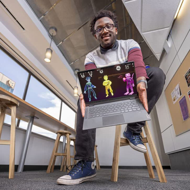 Jaylen Dunbar holding a computer with their digital creation.