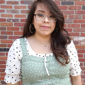 Teiriana Ibarra smiling in front of a brick wall