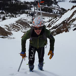 Looking down on Travis Tung hiking up a steep snowy slope