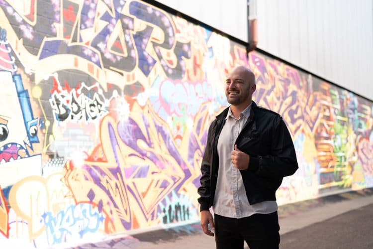 CU Denver student standing in front of street art