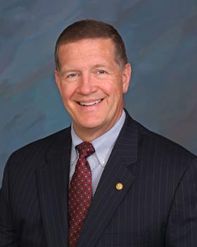 headshot of Harry Bull from the chest up smiling in business suit with tie