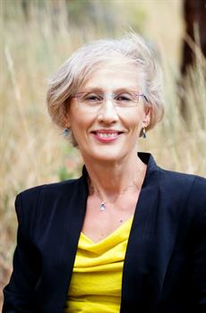 Headshot of Sue Stash in business attire smiling in front of field outdoors