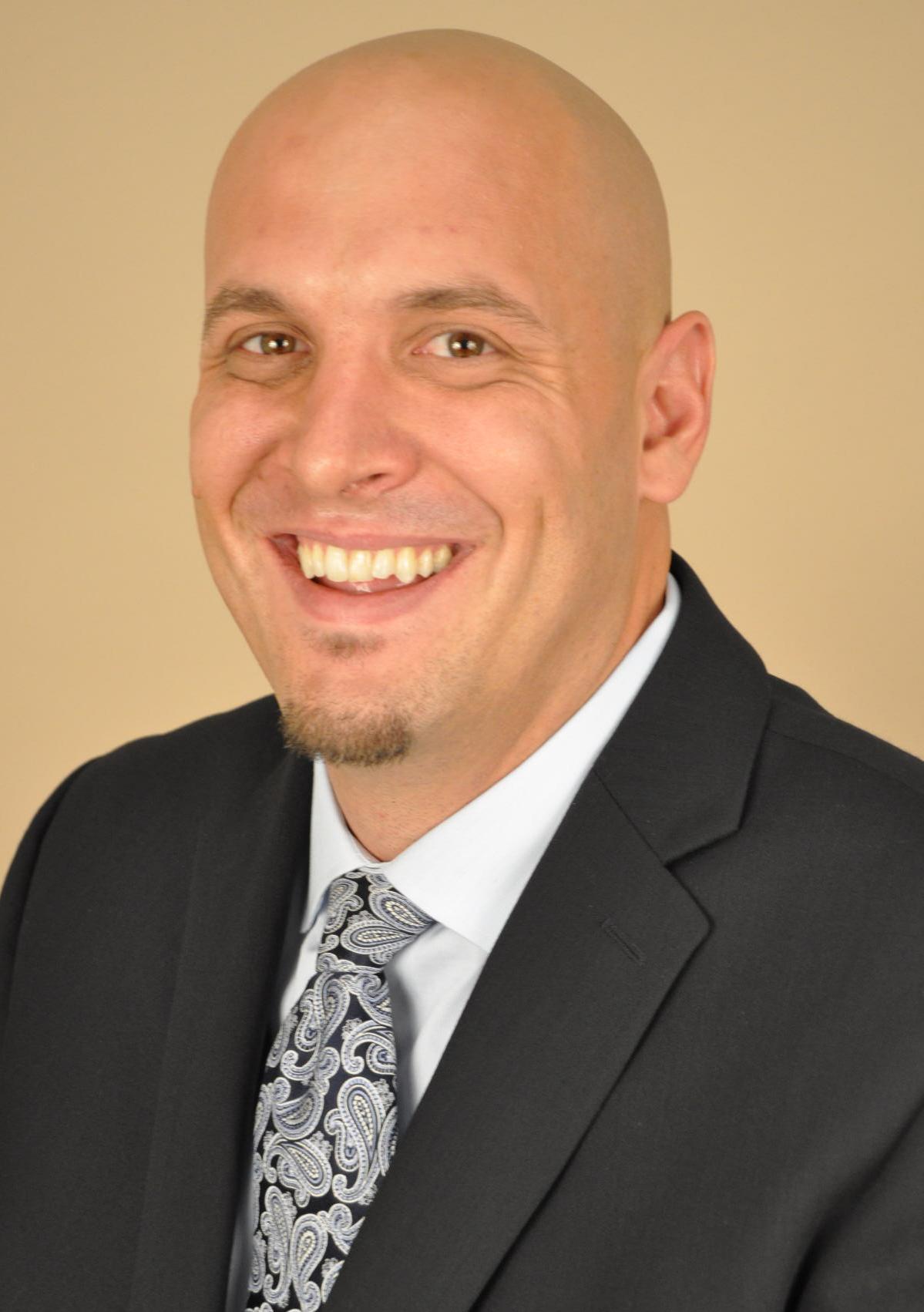 headshot of Christopher J Kleck smiling in business suit and tie