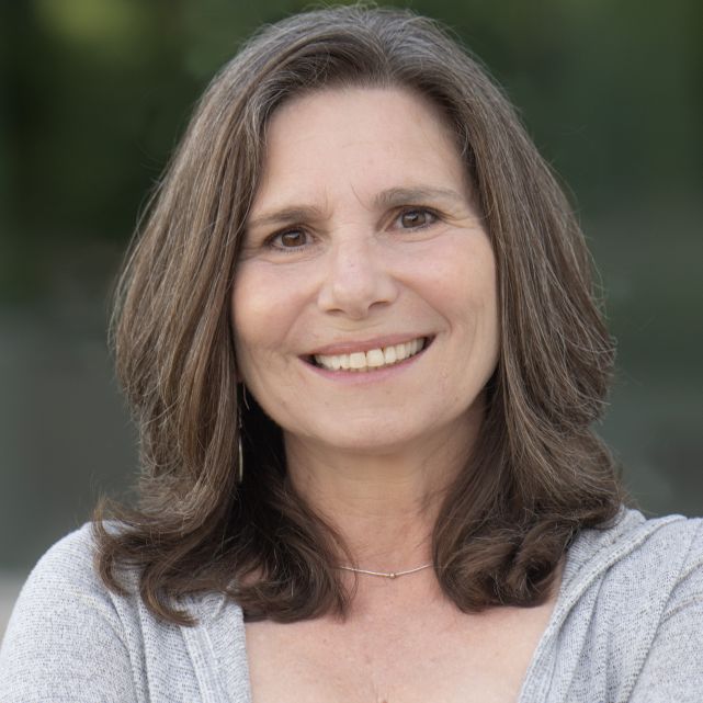 Headshot of Aleaza Goldberg from shoulders up smiling in business casual blouse.