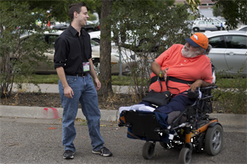 student interacts with a gentleman who uses a wheelchair