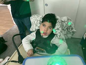 Young child smiling and standing independently using his Gait Trainer.