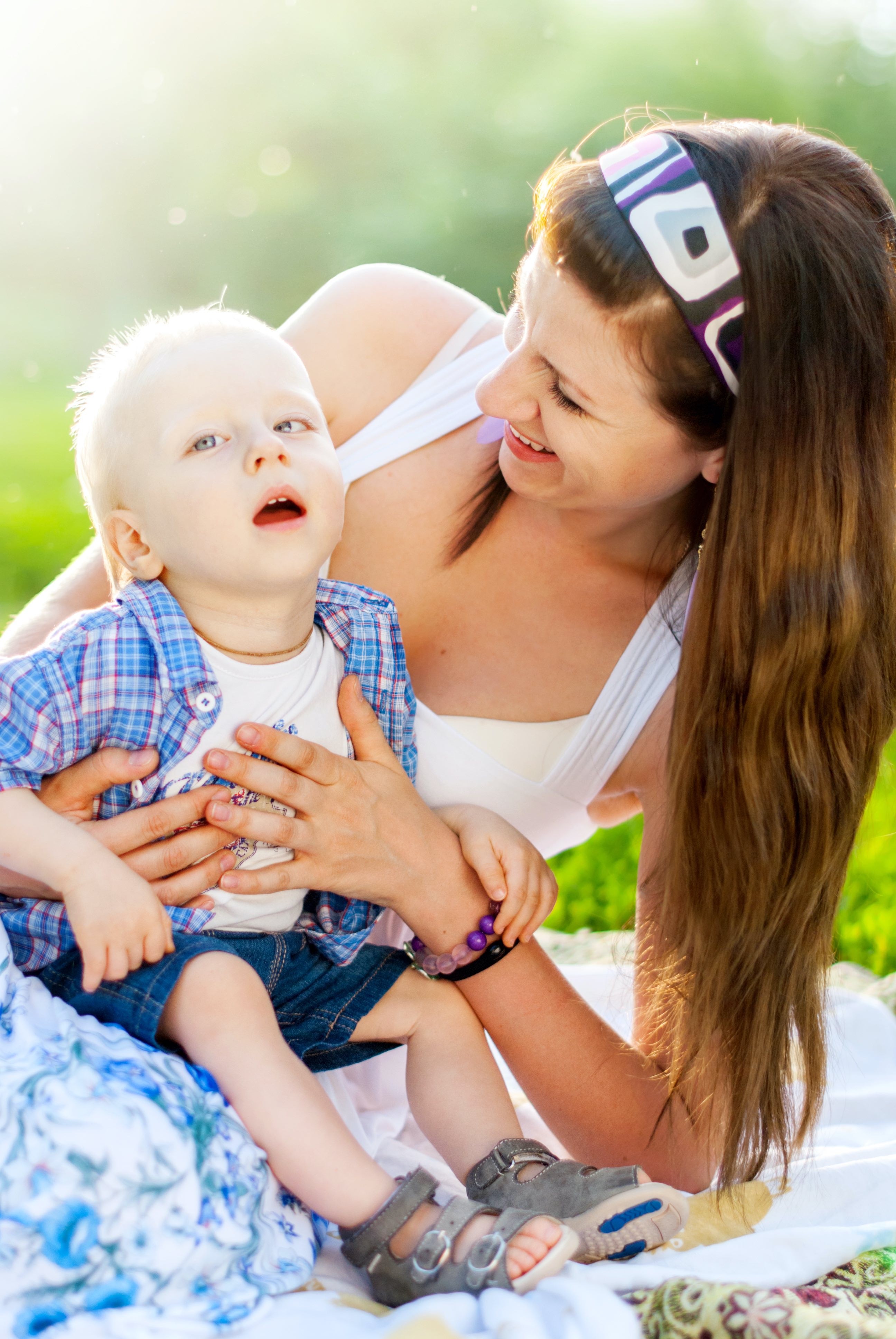 Mom holding and smiling at toddler with disability.