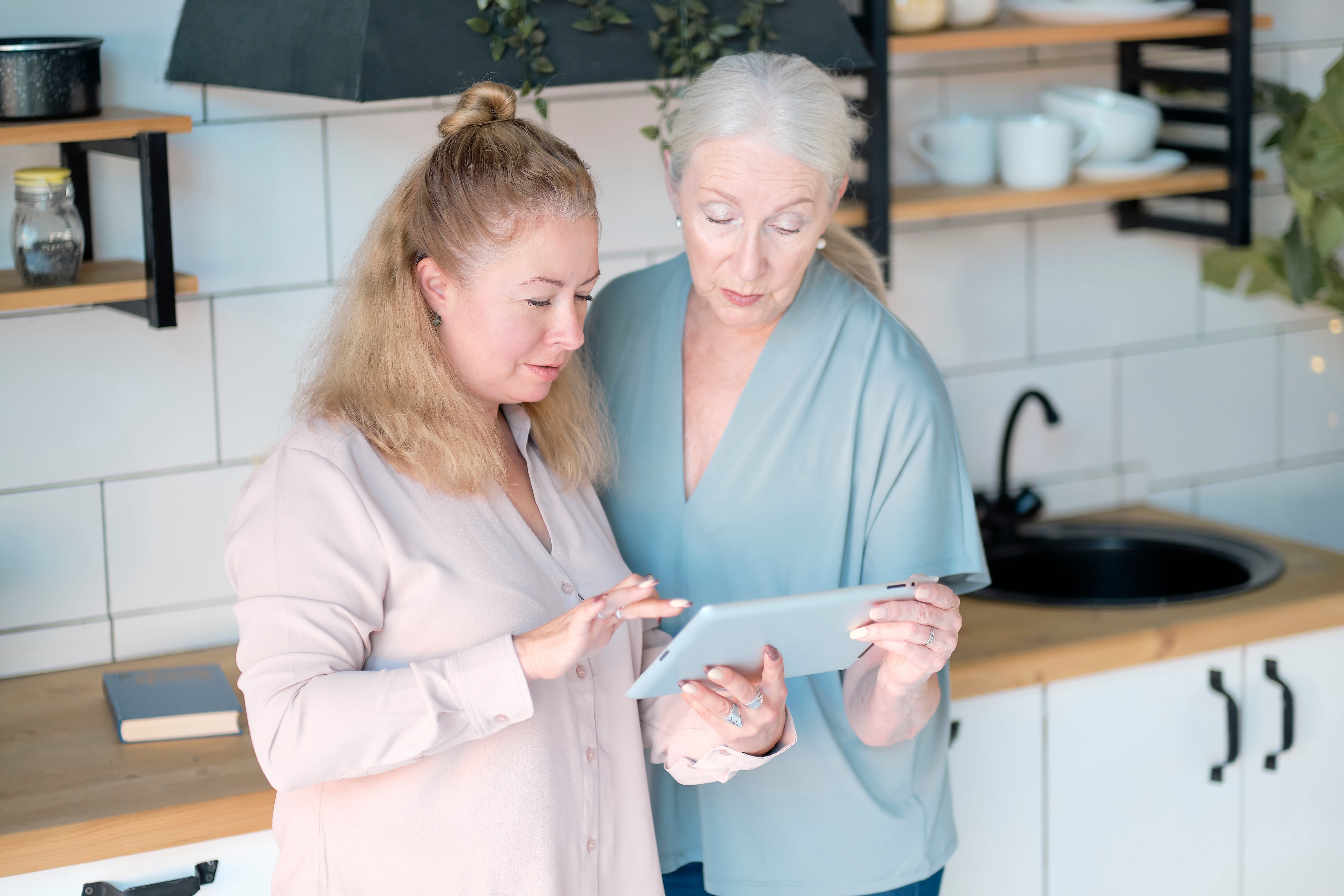 A Tech Mentor supports an older woman with a tablet