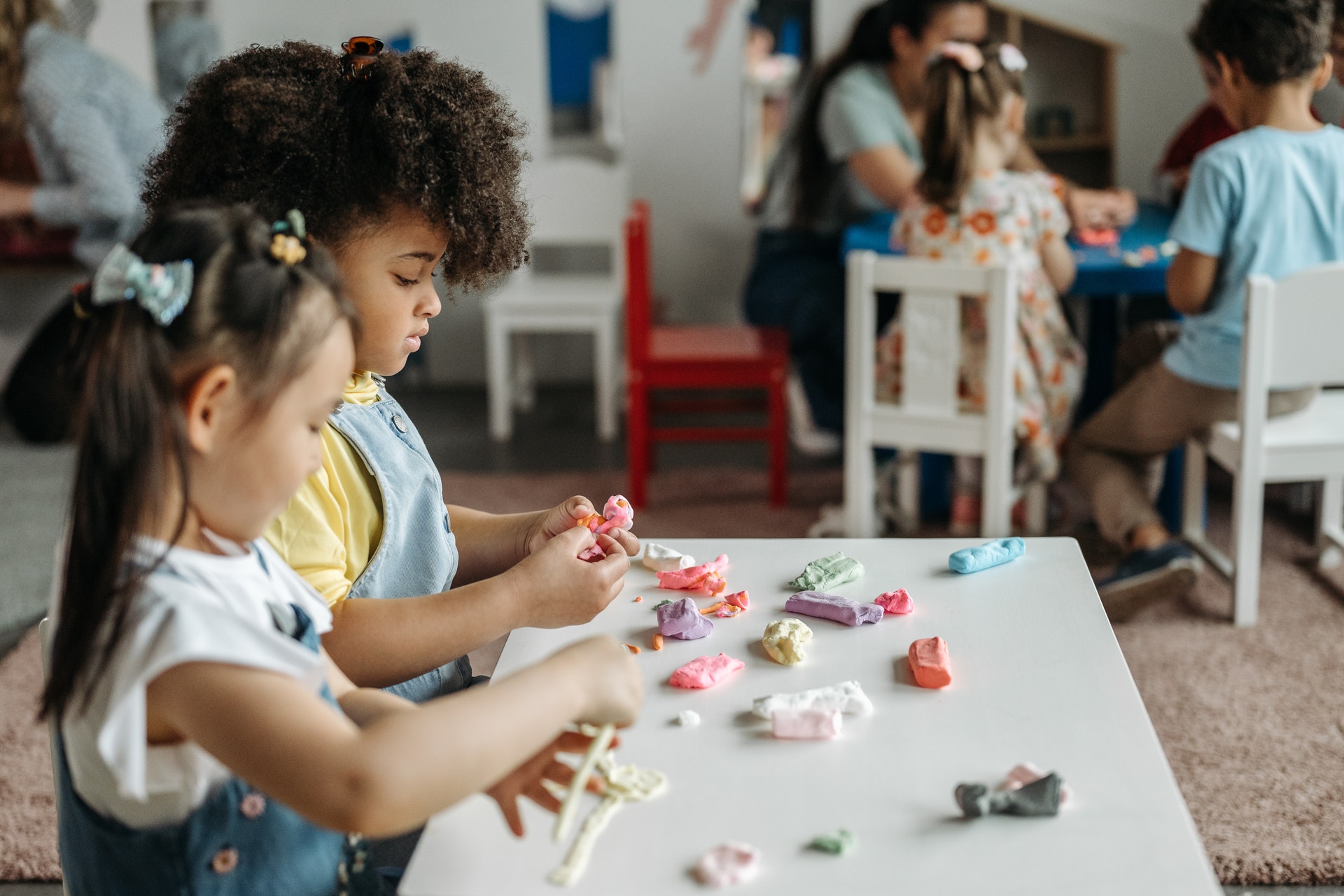 Two kids play with clay at a small table