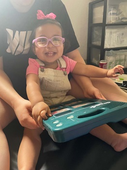 Young girl using GoTalk 4+ to communicate, smiling.